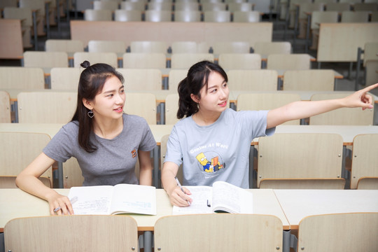 在大学教室里指着左边告诉同学的女学生