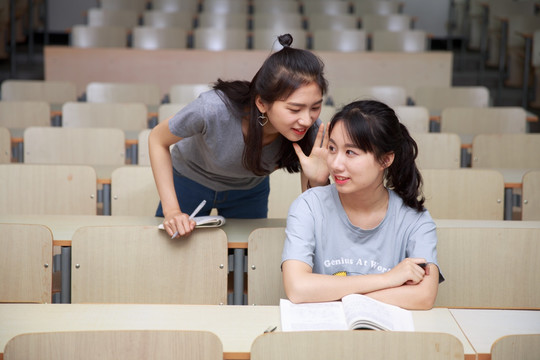 在大学教室里说悄悄话的女大学生