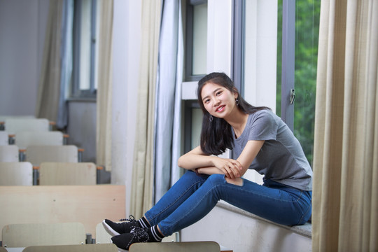 坐在教室窗台上看着前方的女学生