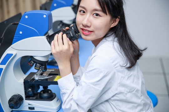 使用显微镜做实验的女学生