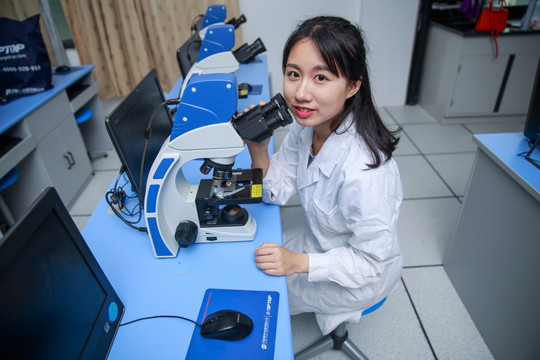 女学生使用显微镜做着实验