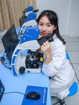微笑着使用显微镜的女学生