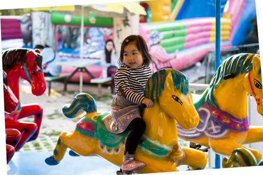 在游乐园微笑着骑旋转木马的女孩