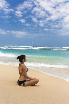坐在沙滩上练瑜伽的女人