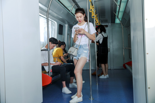 站在地铁里用手机的女乘客