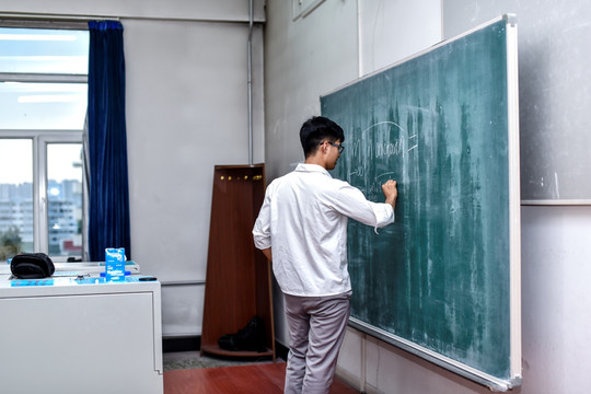 大学生在黑板上写字
