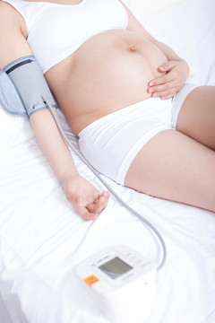 孕妇躺在床上检查血压