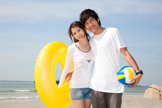年轻情侣在海边度假玩沙滩排球