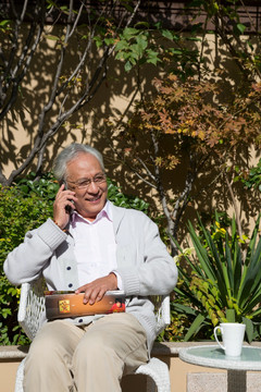 老男人在花园里看书打电话