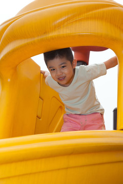 小男孩在幼儿园内玩滑梯