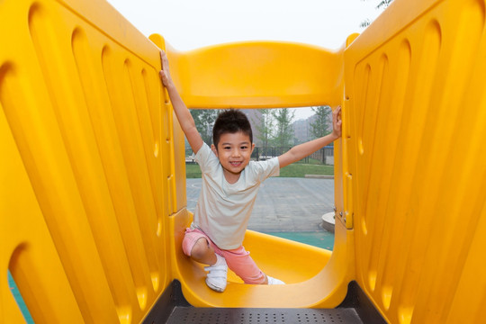 小男孩在幼儿园内玩滑梯