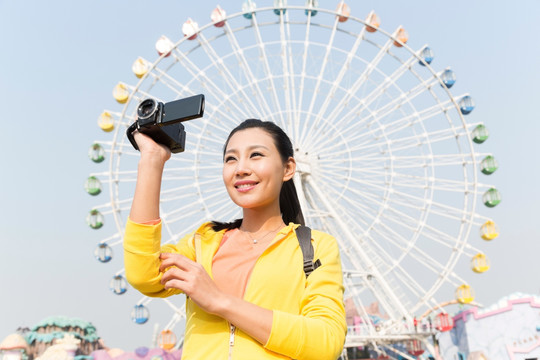 年轻女人手拿DV在游乐园