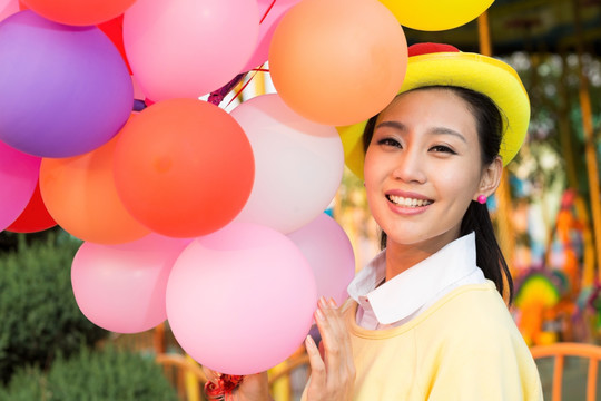 年轻女人牵着气球在游乐园