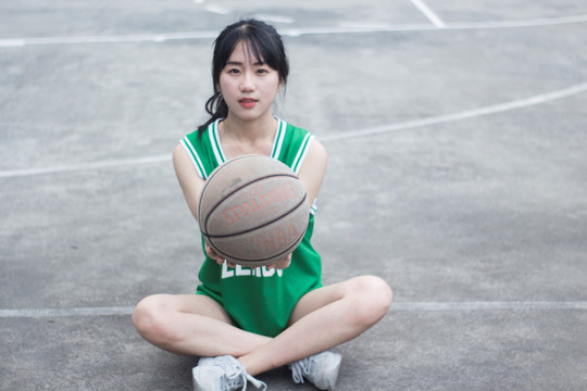 盘腿坐着拿着篮球的女学生