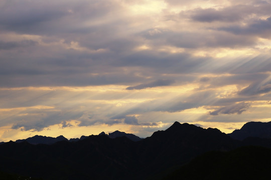 透过浓浓云射向群山的夕阳