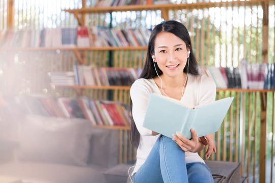 年轻女子在书店看书听音乐