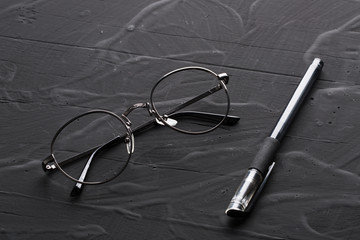 黑色背景上的眼镜和笔
