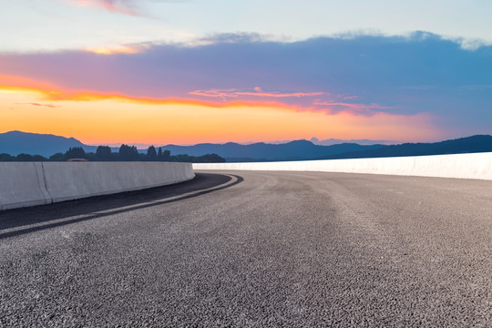 前景是沥青道路的湖泊晚霞