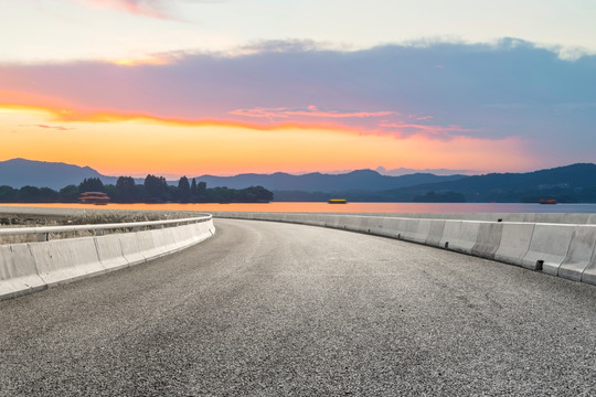 前景是沥青道路的湖泊晚霞