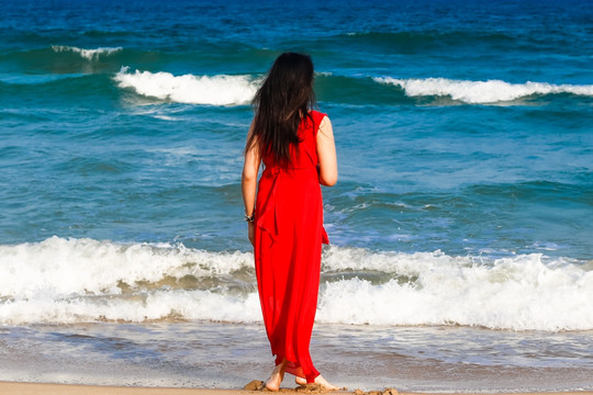 海边穿红裙子的女人背影