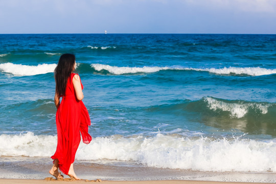 海边穿红裙子的女人背影