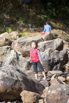小女孩站在溪水石头上