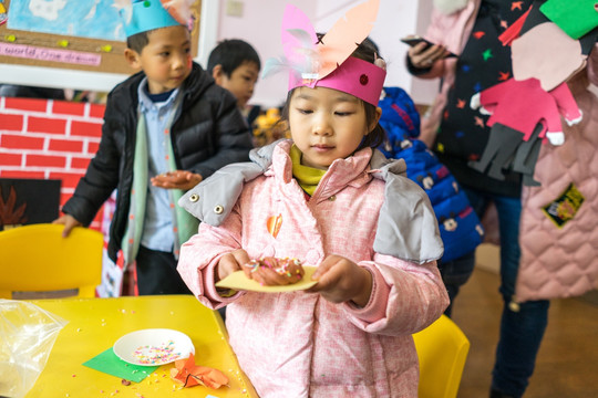 在幼儿园里拿着甜甜圈的小女孩