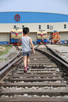 小男孩走在铁轨道路上