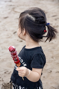 海边吃糖葫芦小女孩