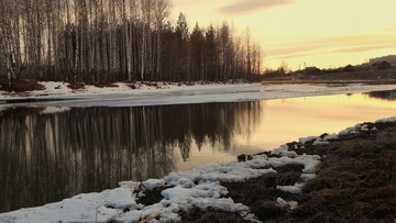 早春残雪夕阳河边树木倒影晚霞