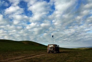 草原蓝天白云下的吉普车