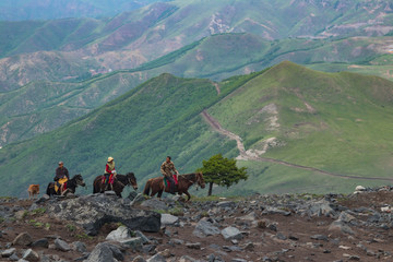 在山上骑马的旅游者）