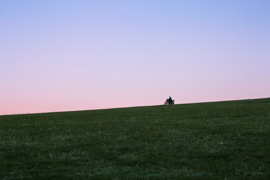 傍晚草原天边骑摩托的蒙古人