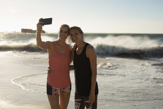 女运动员在海滩用手机自拍