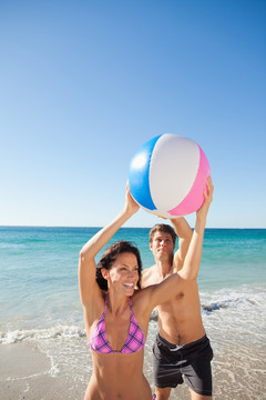 泳装情侣在沙滩上玩球