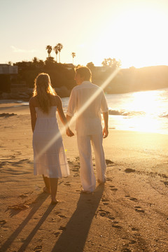 日落时分在海滩散步的情侣	
