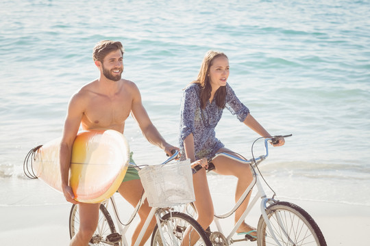 快乐的一对在海滩骑自行车