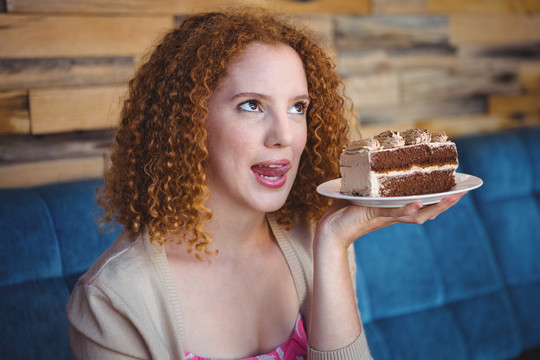 微笑的女人拿着一块巧克力蛋糕