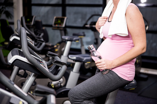 孕妇在健身房骑自行车