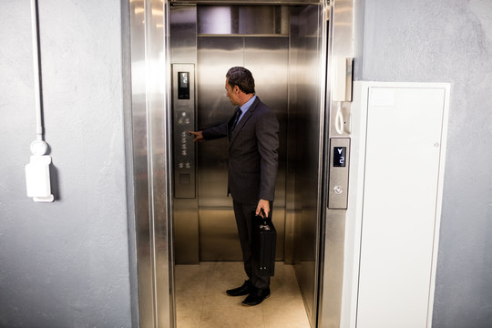 微笑的商人在办公室按电梯按钮