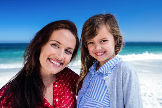 妈妈和女儿在海滩上手挽着手微笑