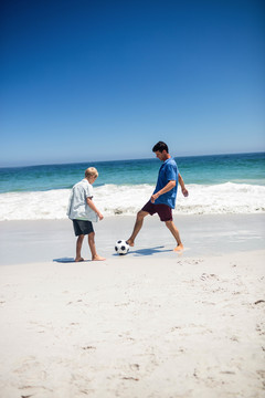爸爸和儿子在海滩上踢足球