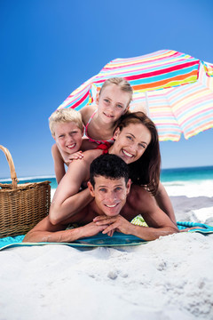 可爱的一家人躺在海滩上的毛巾上
