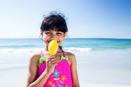 可爱的女孩在海滩上吃冰淇淋