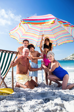 可爱的一家人把伞放在海滩上