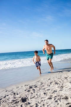 父亲和儿子在海滩上奔跑