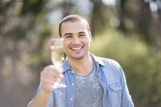 微笑的男人在花园里拿着一杯香槟