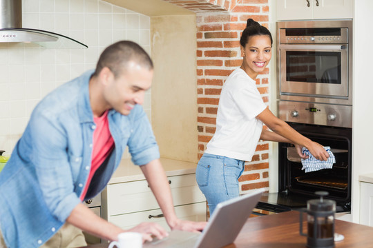 年轻人用电脑和女朋友在厨房里烤
