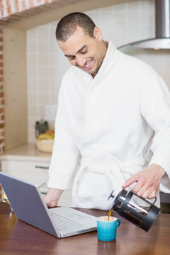 男人在厨房里喝咖啡用笔记本电脑