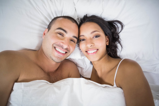 年轻夫妇在家里抱在床上微笑